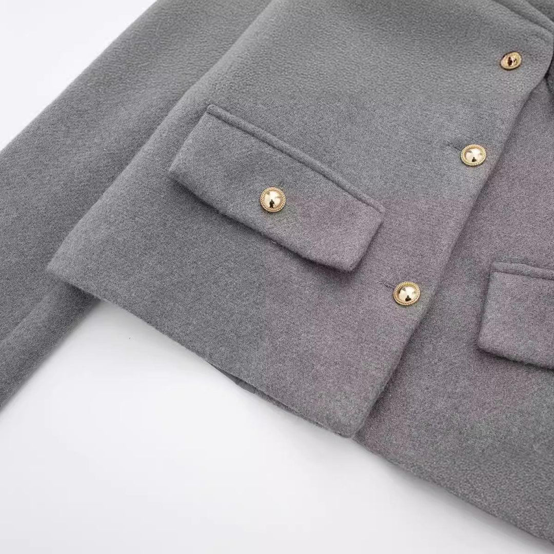 Close-up of gray wool coat with gold button details and flap pocket on white background