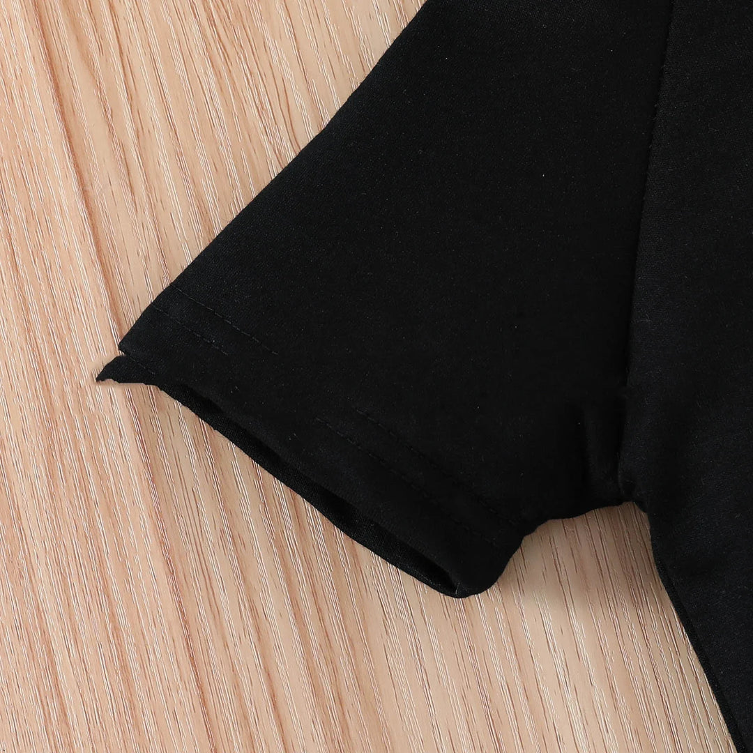 Close-up of a black short sleeve t-shirt on a light wood surface showing detailed stitching