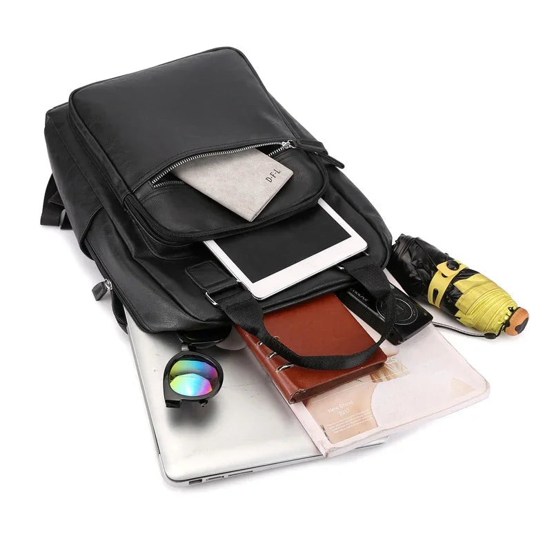 black leather backpack with tablet, notebook, gray wallet, sunglasses, folded umbrella, laptop, and magazine