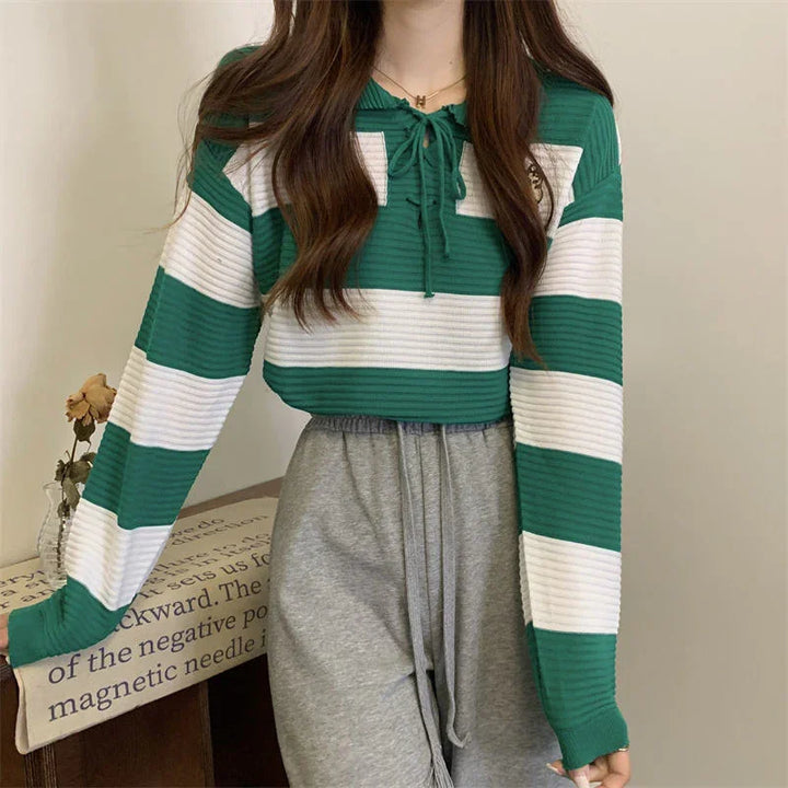 Woman wearing green and white striped knit sweater with lace-up neckline and gray sweatpants
