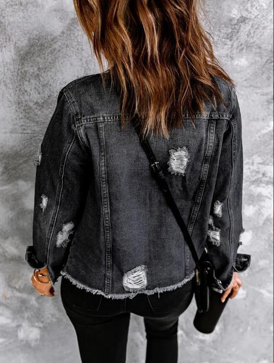 Woman wearing a distressed black denim jacket with ripped details, black pants, and carrying a black crossbody bag
