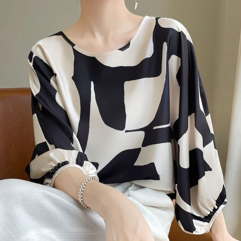 Woman wearing a black and white abstract print blouse with balloon sleeves and a round neckline