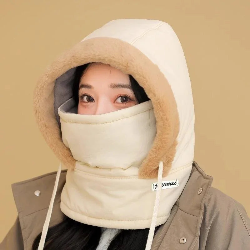 Woman wearing a beige winter hood with fur trim and matching face cover against tan background