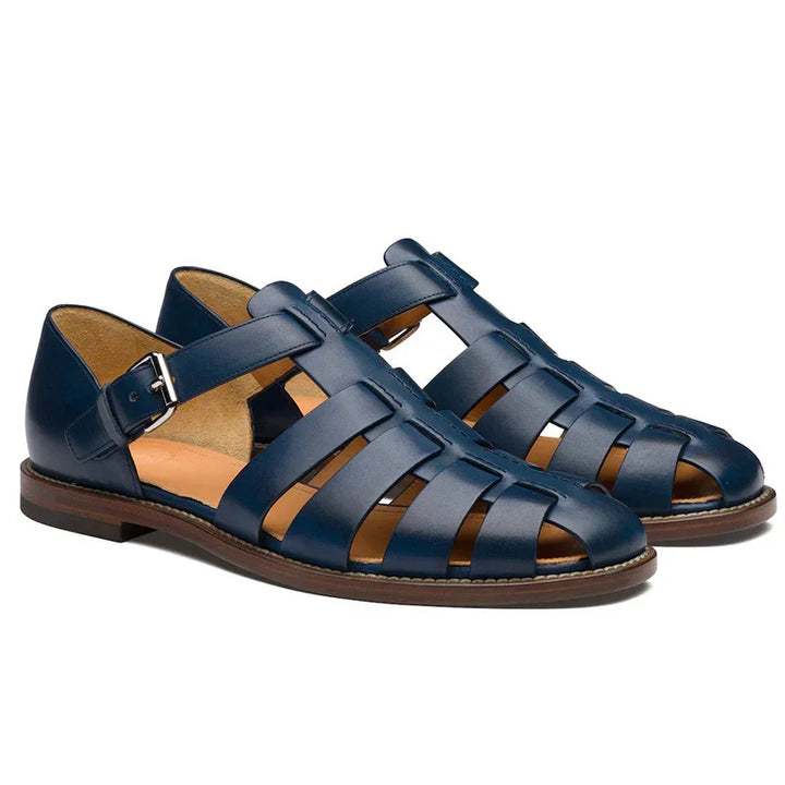Pair of navy blue leather fisherman sandals with buckle straps and brown soles