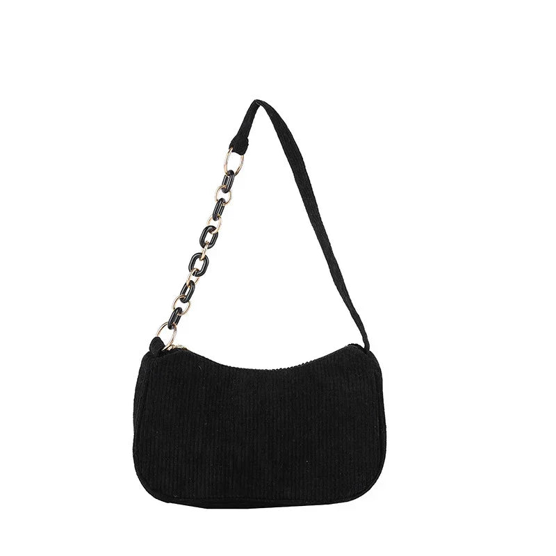 Black corduroy shoulder bag with gold and black chain strap on white background