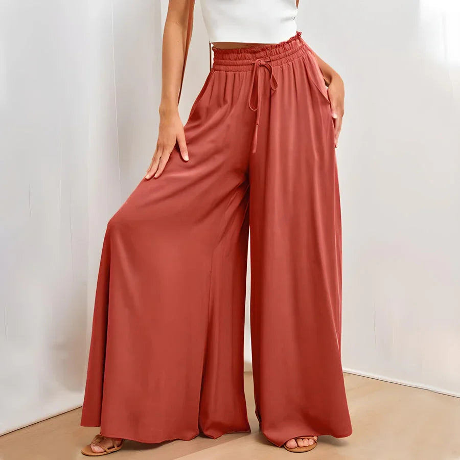 Woman wearing rust red wide-leg pants with elastic waist and drawstring, paired with white crop top