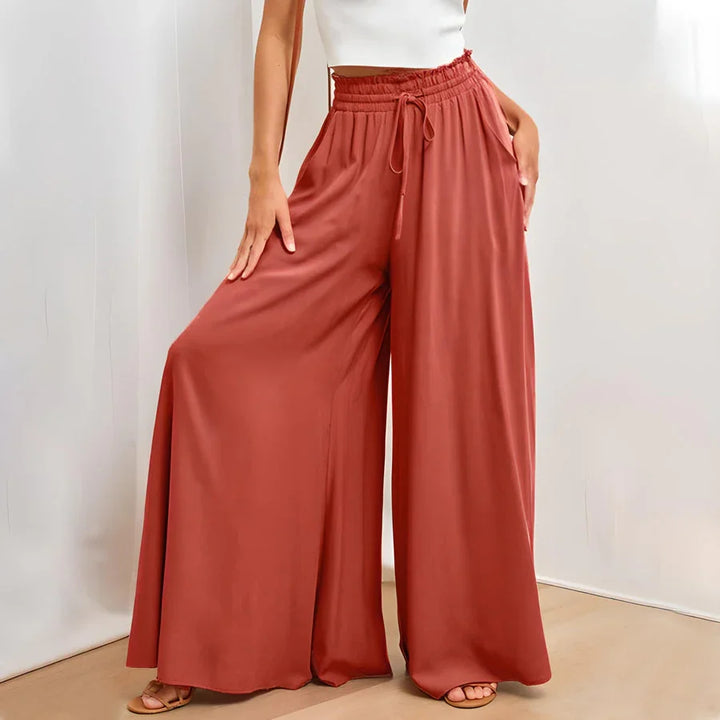 Woman wearing rust red wide-leg pants with elastic waist and drawstring, paired with white crop top