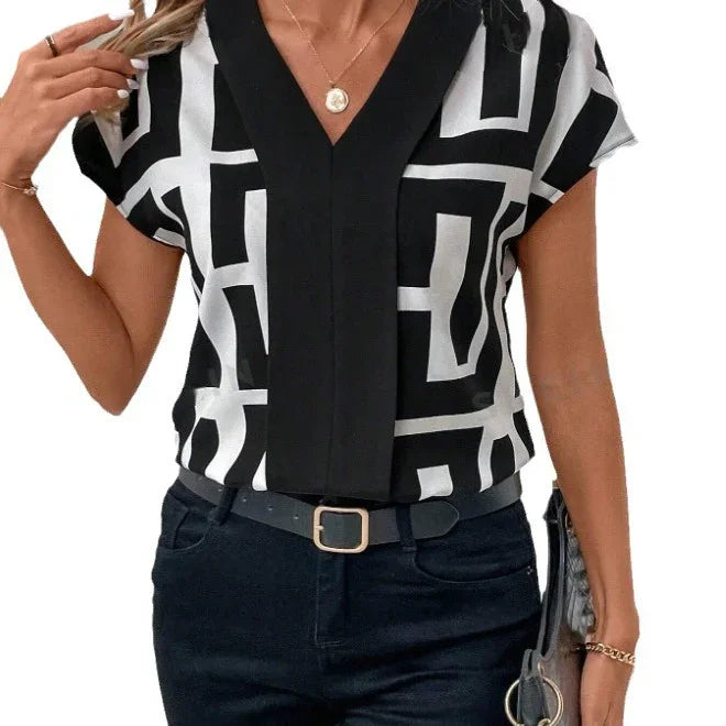 Woman wearing black and white geometric print short-sleeve blouse with black pants and belt