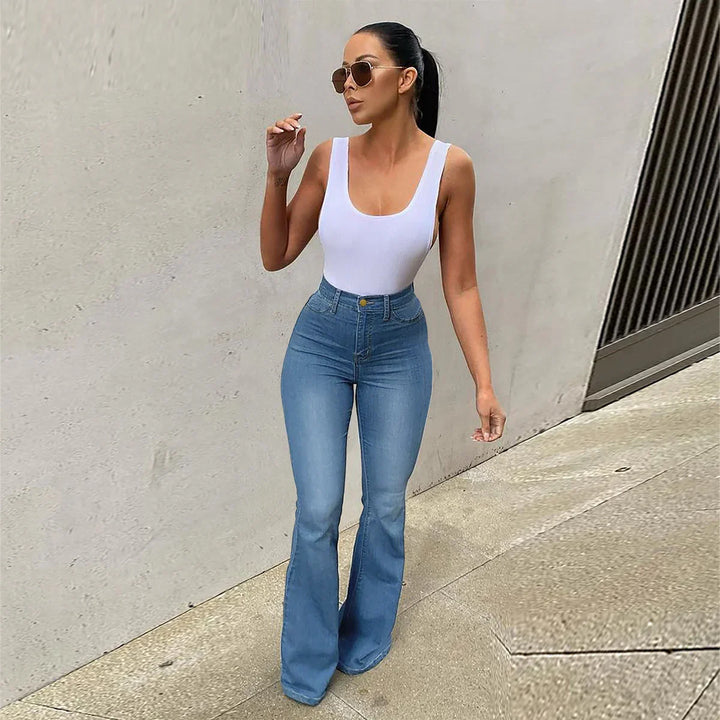 Woman wearing white sleeveless top and high-waisted flared blue jeans with sunglasses walking outdoors