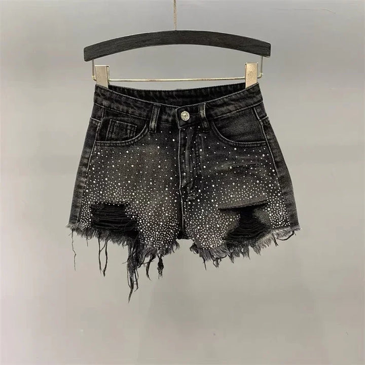Black distressed denim shorts with rhinestone embellishments and frayed hems on a hanger