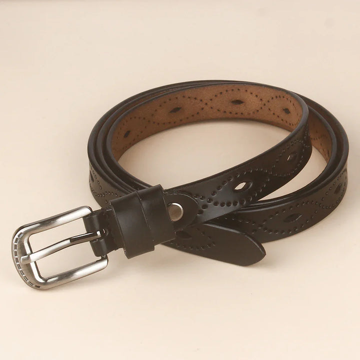 Black leather belt with decorative punched patterns and silver metal buckle on beige background