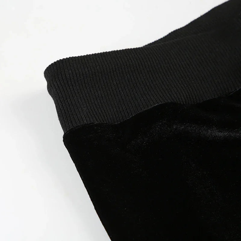 Close-up of black velvet pants with ribbed elastic waistband on white background