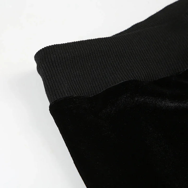 Close-up of black velvet pants with ribbed elastic waistband on white background