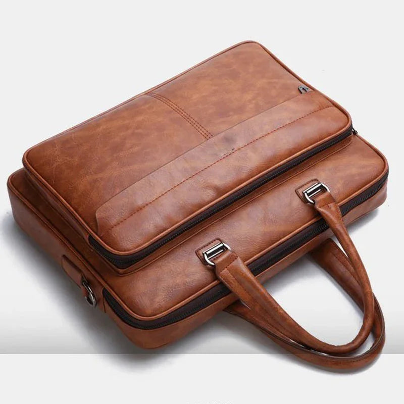 Brown leather briefcase with two handles and zippered compartments on a white background