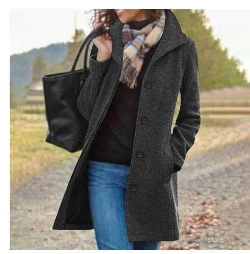 Woman wearing dark gray buttoned wool coat, plaid scarf, blue jeans, carrying black tote bag outdoors