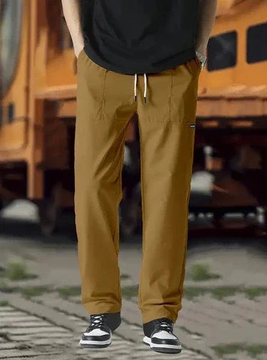 Man wearing brown casual jogger pants with drawstring waist and sneakers outdoors