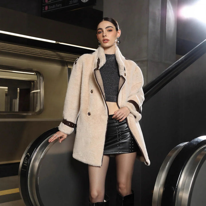 Fashion model in beige faux fur coat, black crop top, and leather skirt posing at subway station