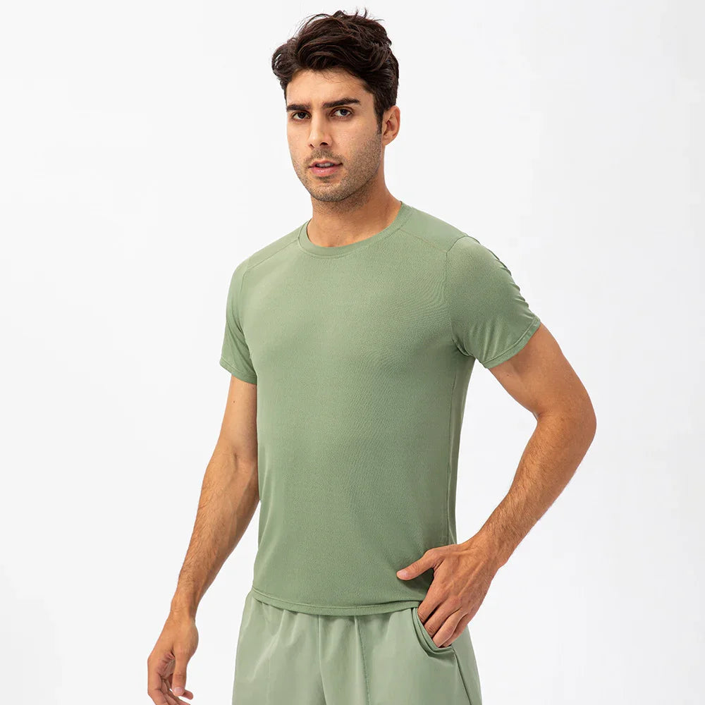 Man wearing light green athletic t-shirt and shorts on white background