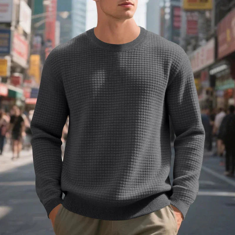 Man wearing dark gray textured sweater with crew neck in urban street setting