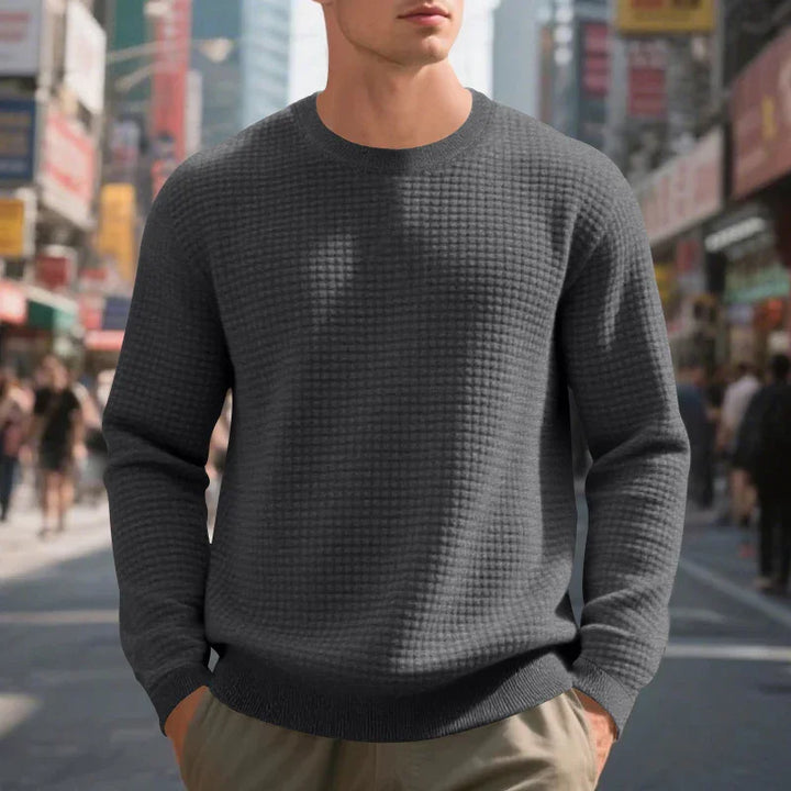 Man wearing dark gray textured sweater with crew neck in urban street setting