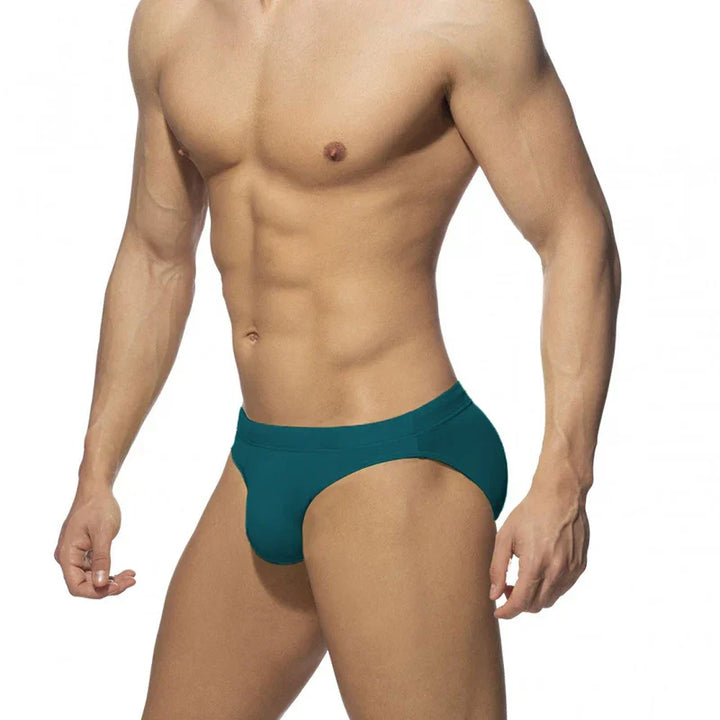 Muscular male torso wearing teal men's underwear briefs on white background