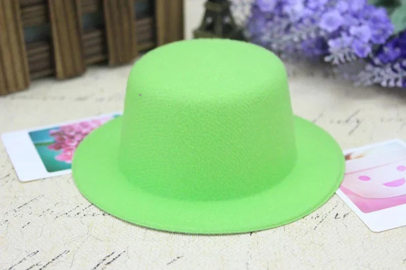 Bright green felt hat displayed on textured beige surface with blurred purple flowers and photos in background