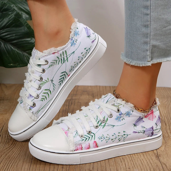 White floral canvas sneakers with frayed edges worn with light blue frayed hem jeans on wooden floor