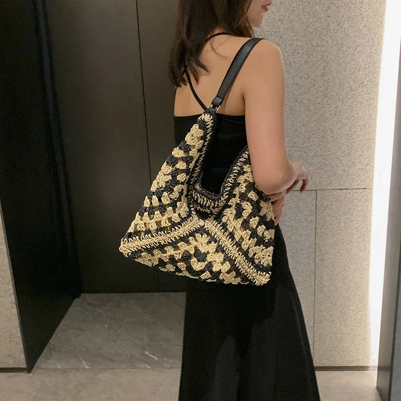 Woman in black dress carrying black and beige crochet shoulder bag indoors