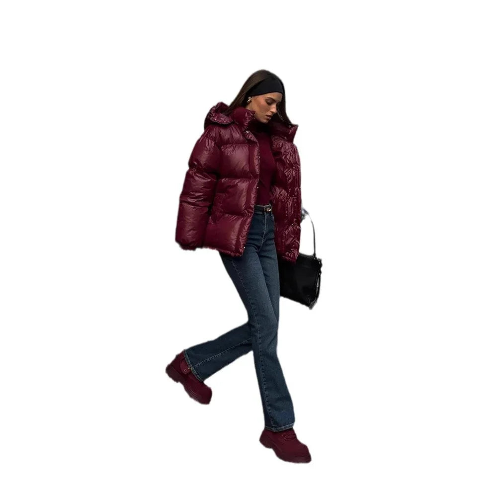 Woman wearing burgundy puffer jacket, dark jeans, matching shoes, black headband, and carrying black handbag