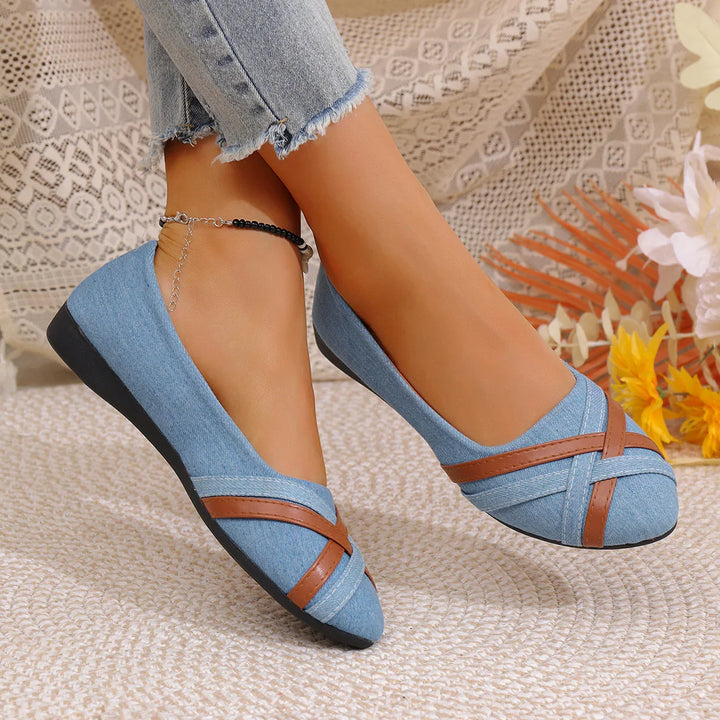 Blue denim flat shoes with brown crisscross straps worn with frayed hem jeans, cozy background