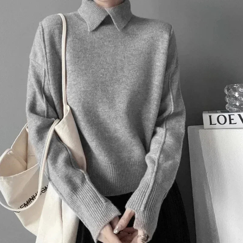 Woman wearing a gray knit sweater with collar and long sleeves, carrying an off-white canvas tote bag