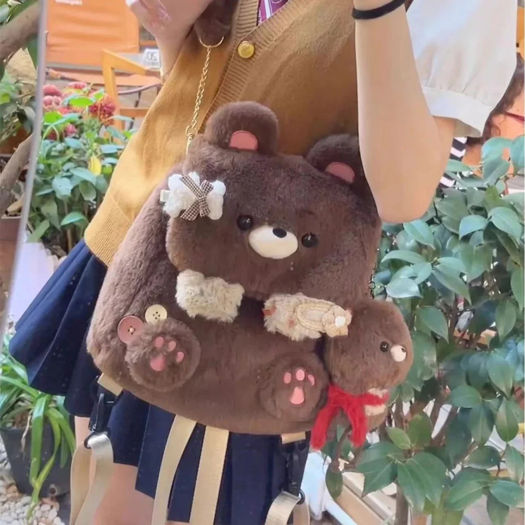 Cute brown plush bear backpack with paw designs and a smaller bear keychain, worn outdoors