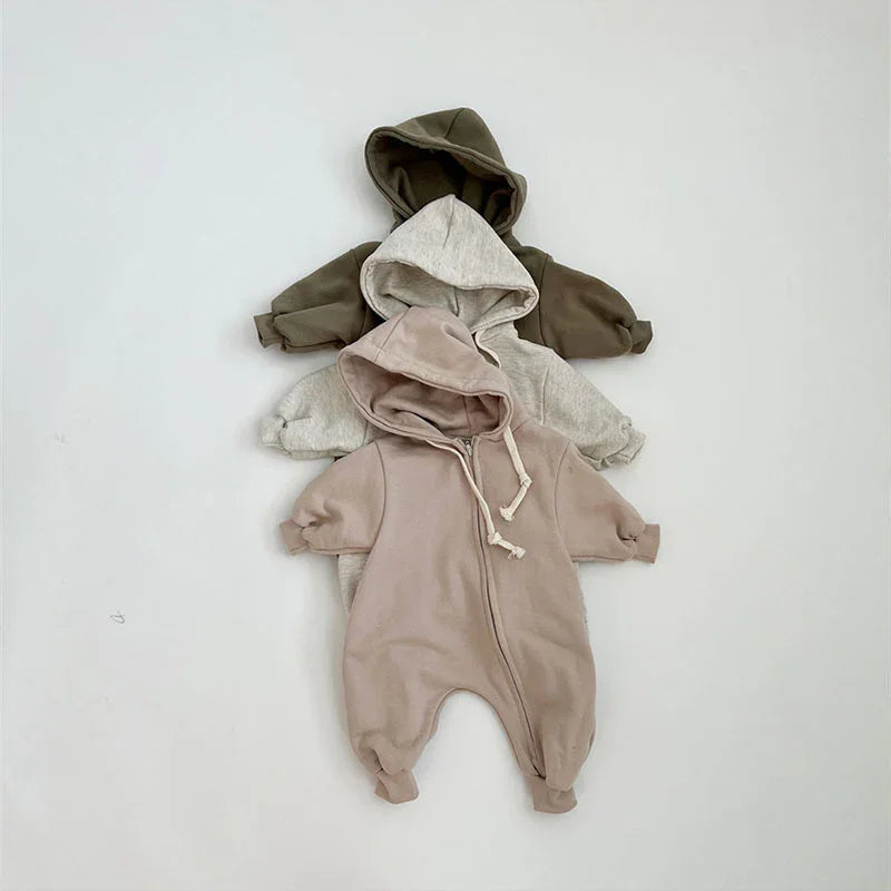 Three baby hooded onesies in muted brown, light gray, and beige, displayed on a light background