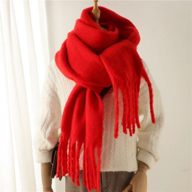 Mannequin wearing a large red fringed scarf and a white textured sweater in a bright room
