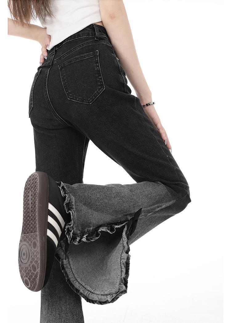 Close-up of black high-waisted jeans with frayed hems and black sneakers with white stripes