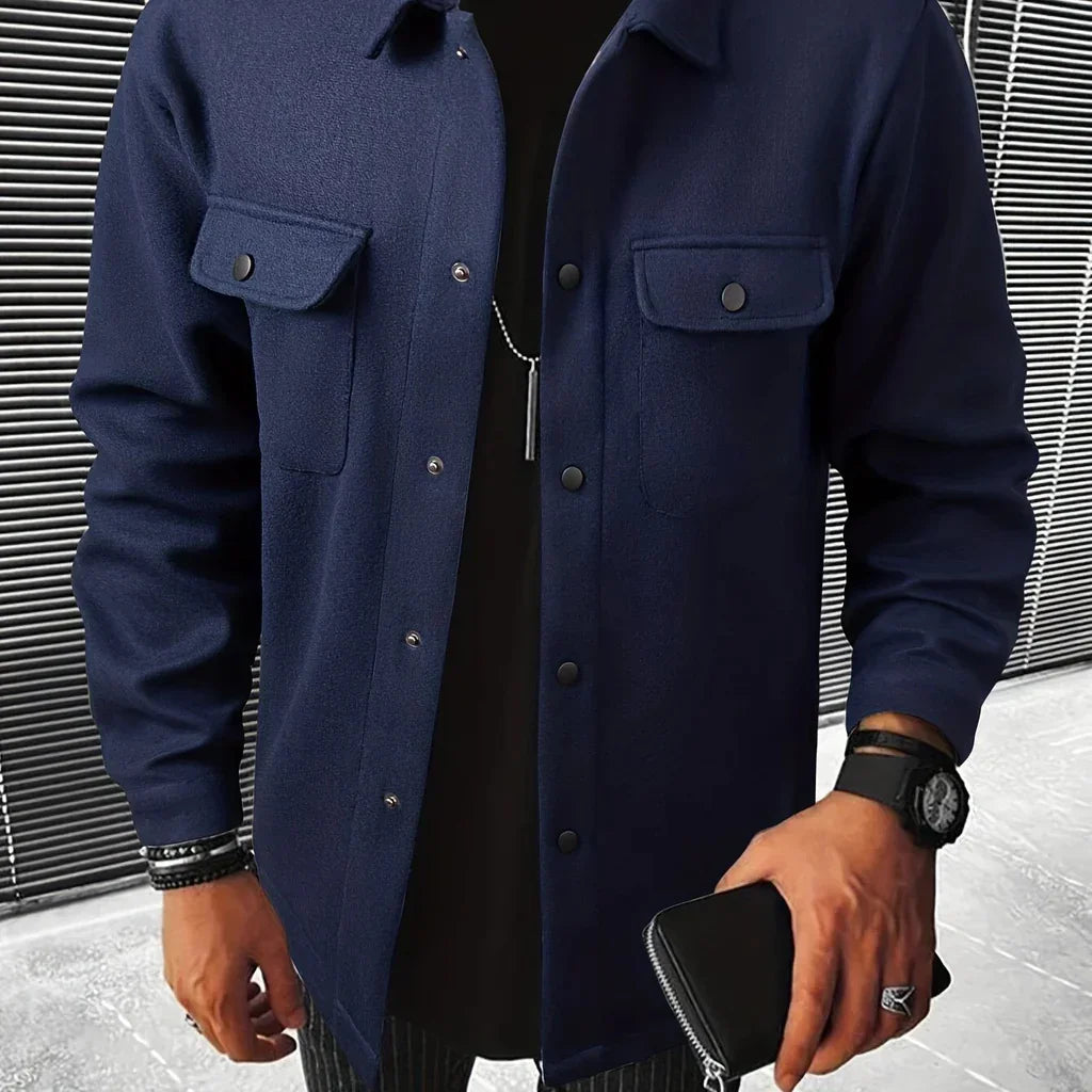 Man wearing navy blue button-up wool jacket with front pockets, holding black wallet, black watch, and bracelets
