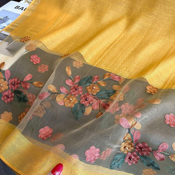 Yellow fabric with sheer embroidered floral border in pink, orange, and green with pearl accents