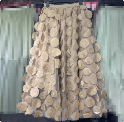 Beige skirt with large circular fabric appliques hanging on a clothing rack