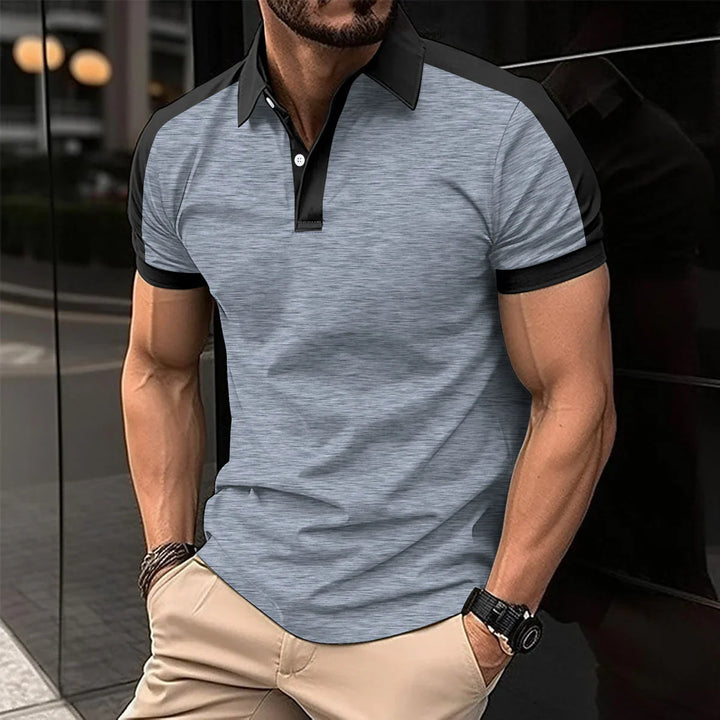 Man wearing fitted grey and black polo shirt with rolled sleeves and beige pants outdoors