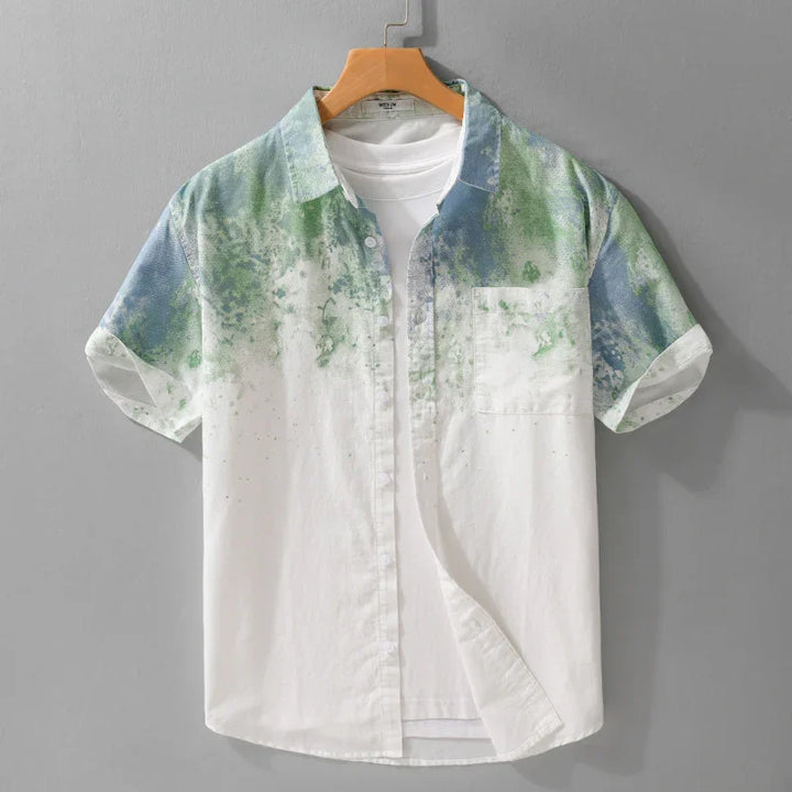 Men's short sleeve button-up shirt with green and blue watercolor print over white fabric
