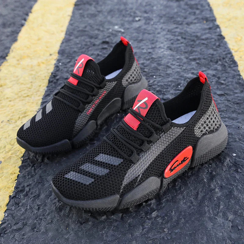 Pair of black and red breathable mesh sports sneakers on textured asphalt with yellow lines