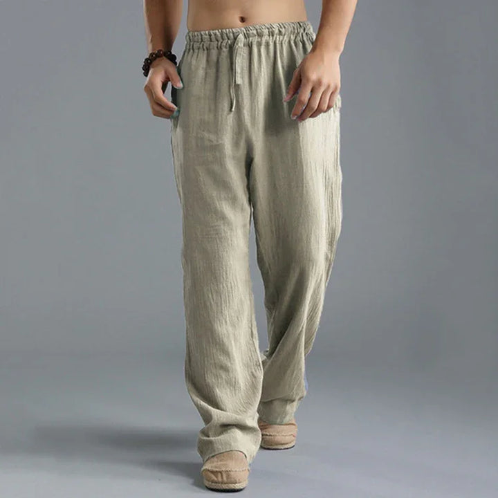 Men's beige linen drawstring pants with loose fit, model wearing casual slippers