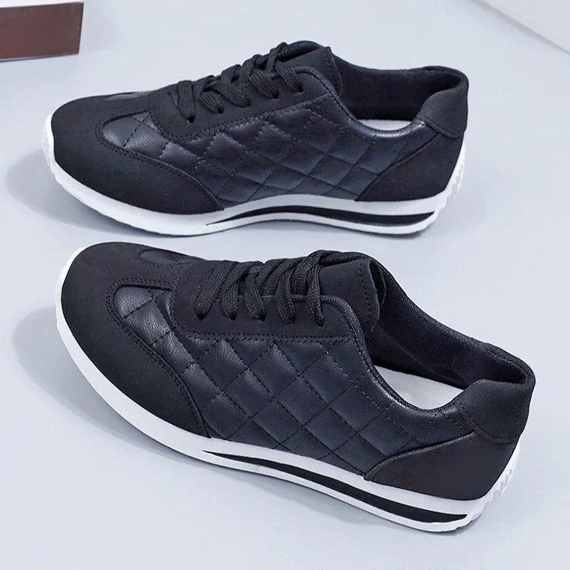 Pair of black quilted leather sneakers with white soles on a white surface