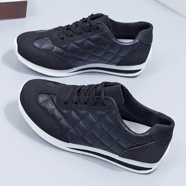 Pair of black quilted leather sneakers with white soles on a white surface