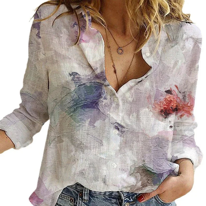 Woman wearing a white floral print button-up blouse with rolled sleeves and blue jeans