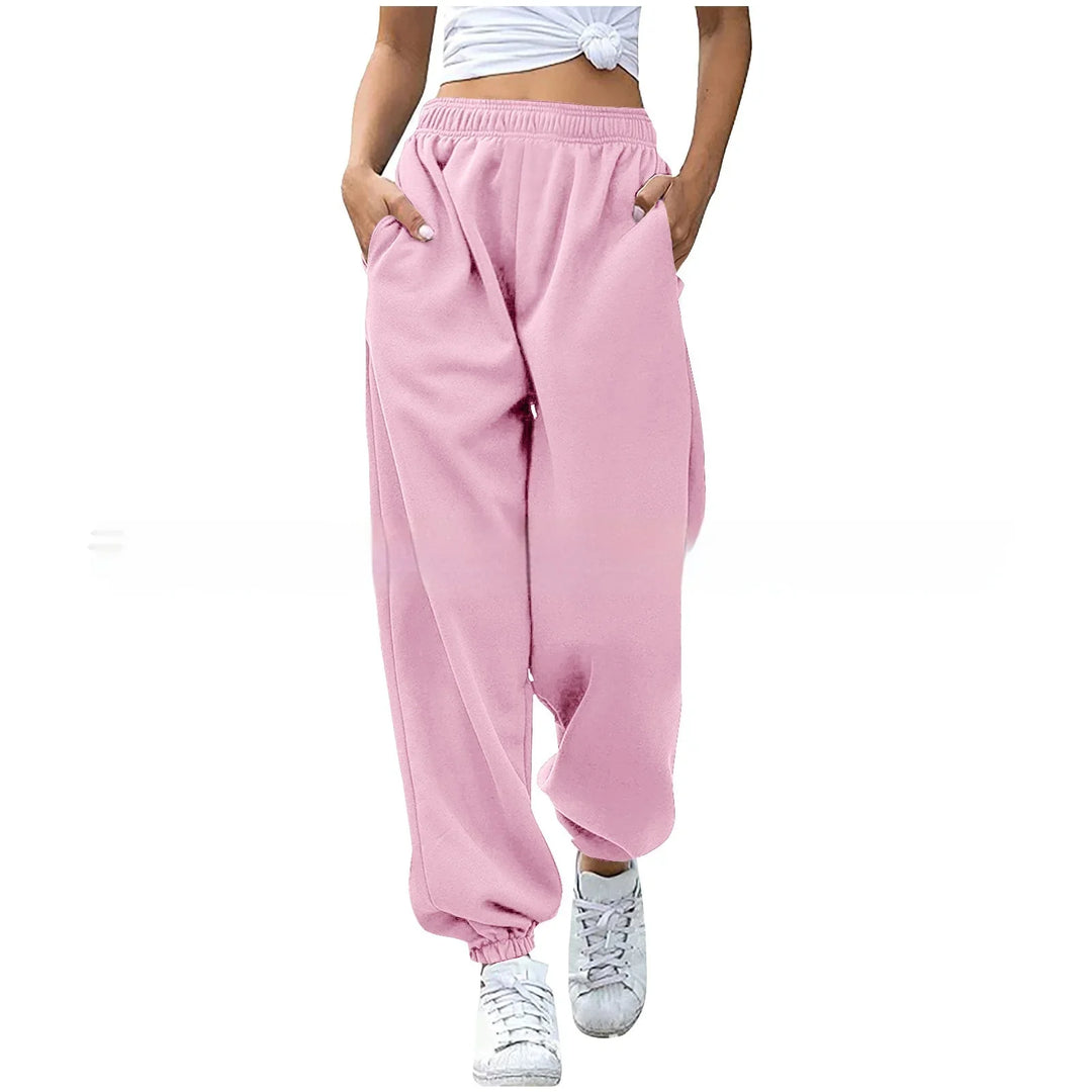 Woman wearing pink loose sweatpants with elastic cuffs and pockets paired with white sneakers