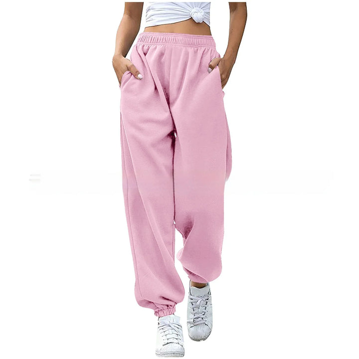 Woman wearing pink loose sweatpants with elastic cuffs and pockets paired with white sneakers