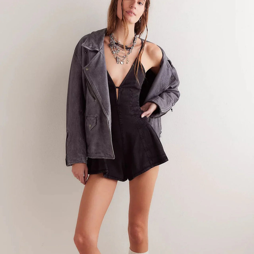 Woman wearing black deep V-neck romper and oversized gray jacket with layered necklaces
