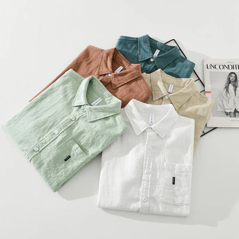 Folded casual linen shirts in white, light green, beige, brown, and teal on white background with fashion magazine