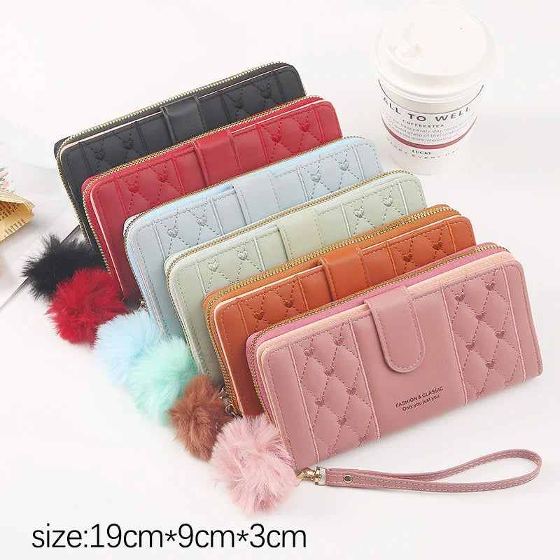Set of six quilted leather wallets in black, red, blue, green, brown, and pink with pom-pom keychains